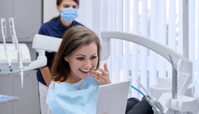 A cosmetic dentistry patient admiring her naturral looking veneers in a mirror at her dentist's office